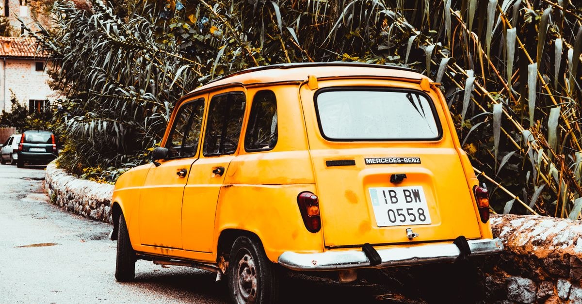 Classic yellow Mercedes-Benz in a quaint Spanish street, evoking nostalgia.