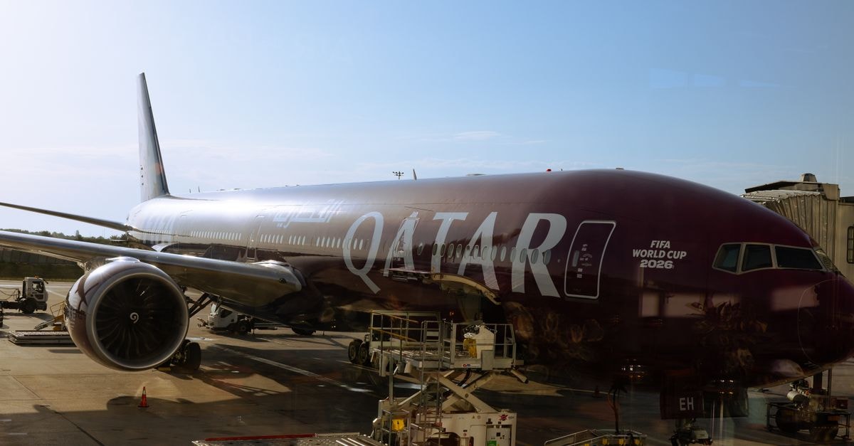 Qatar Airways airplane featuring FIFA World Cup 2026 branding at airport terminal under clear sky.
