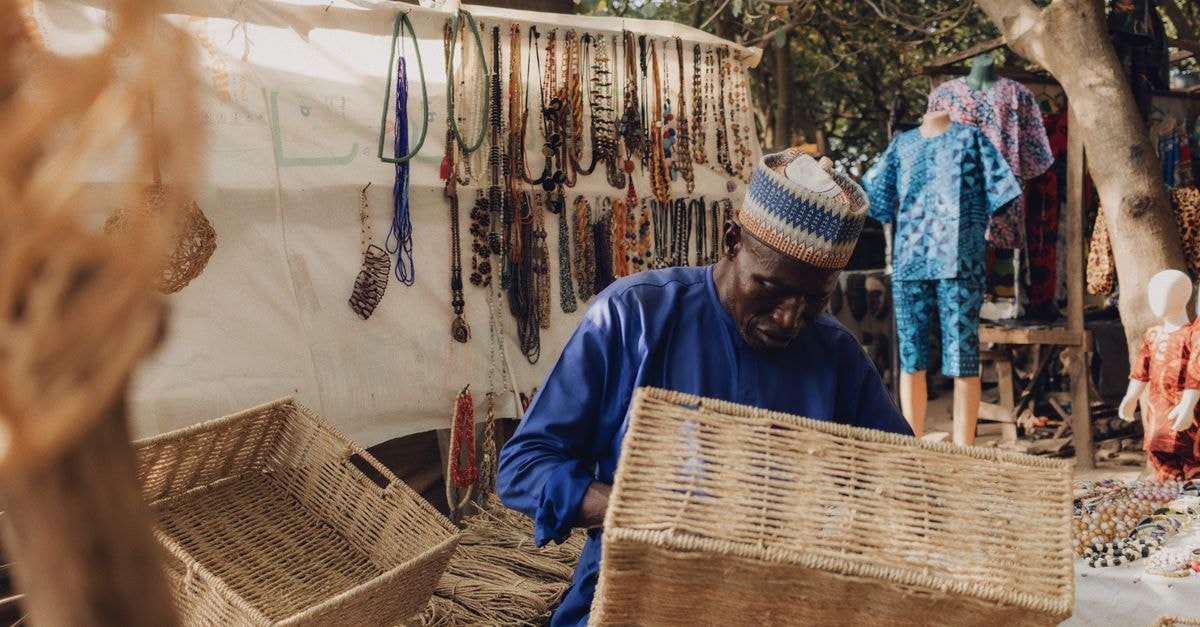 African artisan weaving baskets in a vibrant Nigerian outdoor market.