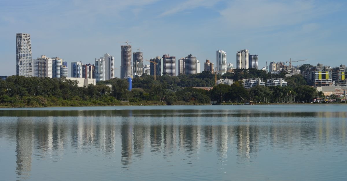 Piracicaba travel guide: riverside calm and a slower Brazilian rhythm Skyline of Curitiba, Brazil, reflecting on a serene lake under a clear blue sky.