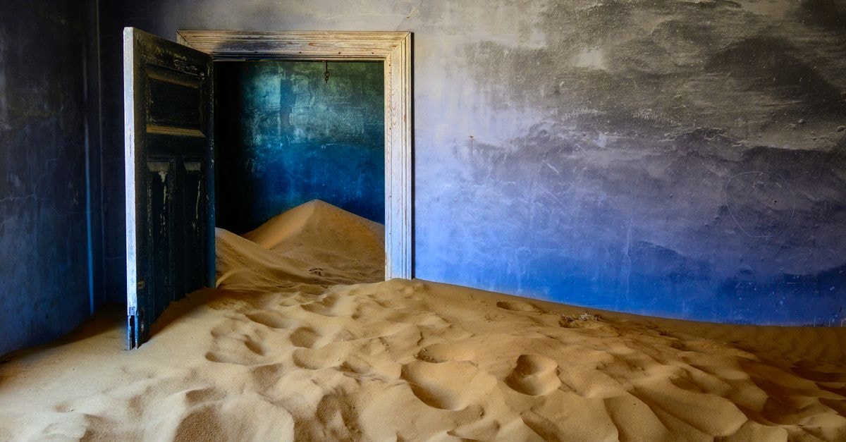 A haunting image of an abandoned room overtaken by sand dunes.