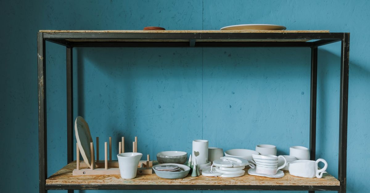 Douala travel guide: ports, plates and practical rhythm Minimalist setup with white ceramic dishes on a rustic shelf against a blue background.