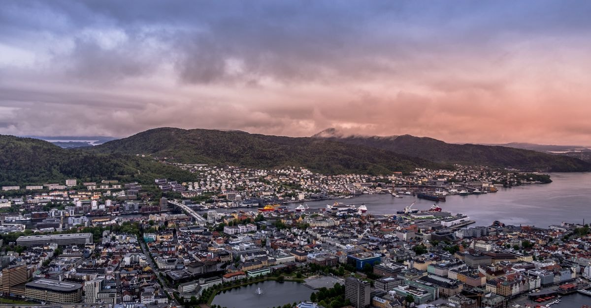 A captivating aerial shot of Bergen, Norway at dusk showcasing the cityscape, harbor, and surrounding mountains.