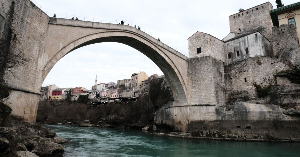 Mostar Travel Guide: Crossing the Old Bridge on Foot Stari Most bridge arching over Neretva River, Mostar, showcasing historic architecture.