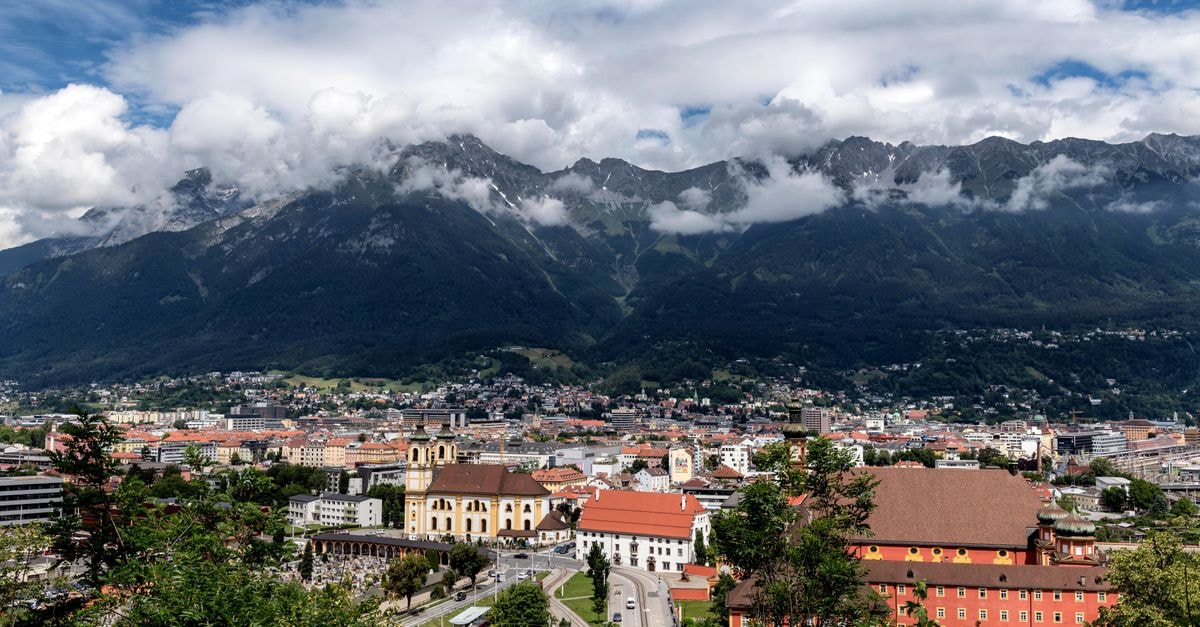 Innsbruck Travel Guide: Planning Tips, Costs and Things to Do A breathtaking aerial view of Innsbruck, Austria, framed by majestic mountains and vibrant urban life.
