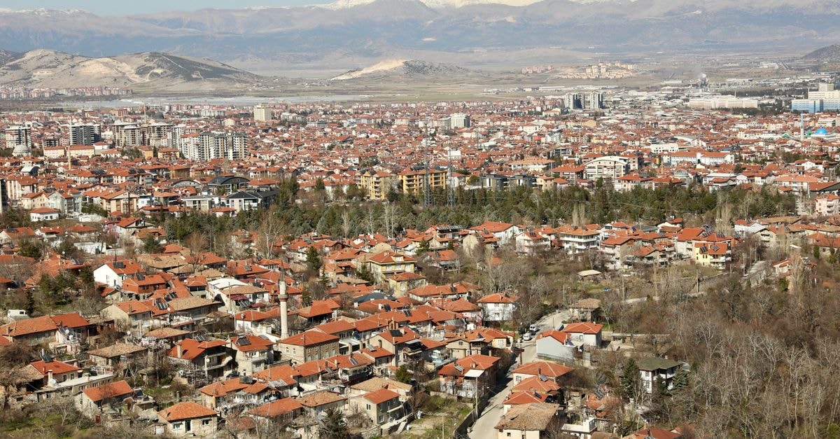 Aerial view of Isparta cityscape with red-roofed houses and distant mountains in Türkiye.