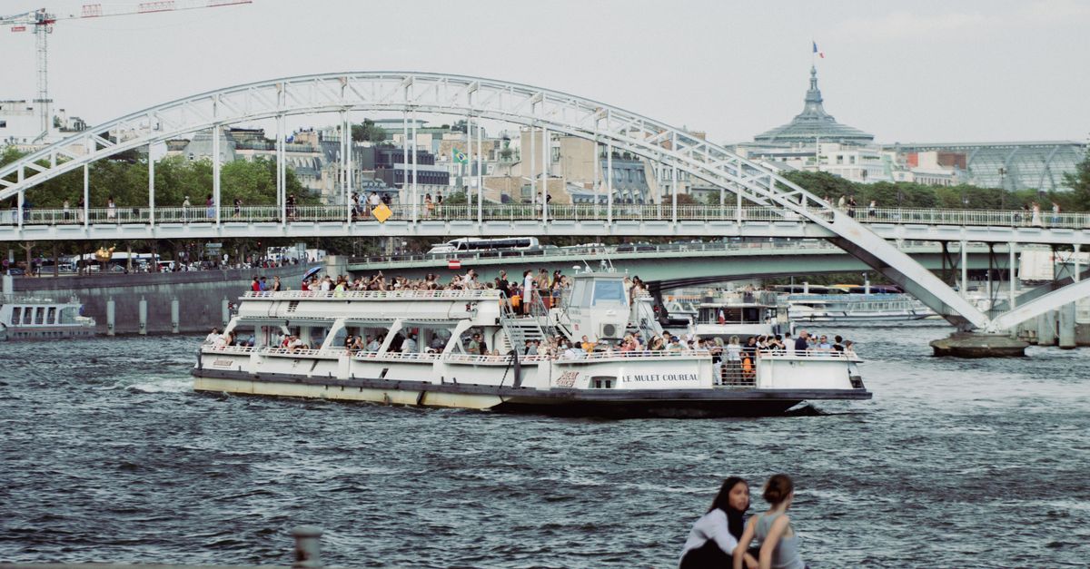 Tour boat cruising on the Seine River near a bridge in Paris, France.