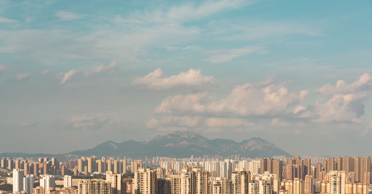 An expansive cityscape with skyscrapers and mountains under a blue sky.