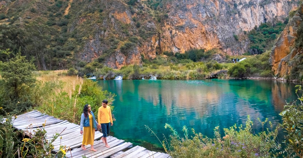 Tepic Travel Guide: Planning Tips, Costs and Things to Do Couple walking on a wooden dock at Huancaya, Perú, surrounded by vibrant cliffs and turquoise waters.