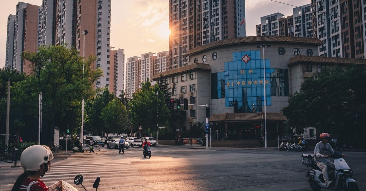 Zhengzhou Travel Guide: A Central China Hub Worth Discovering A bustling city intersection at sunset, highlighting urban life among towering skyscrapers.