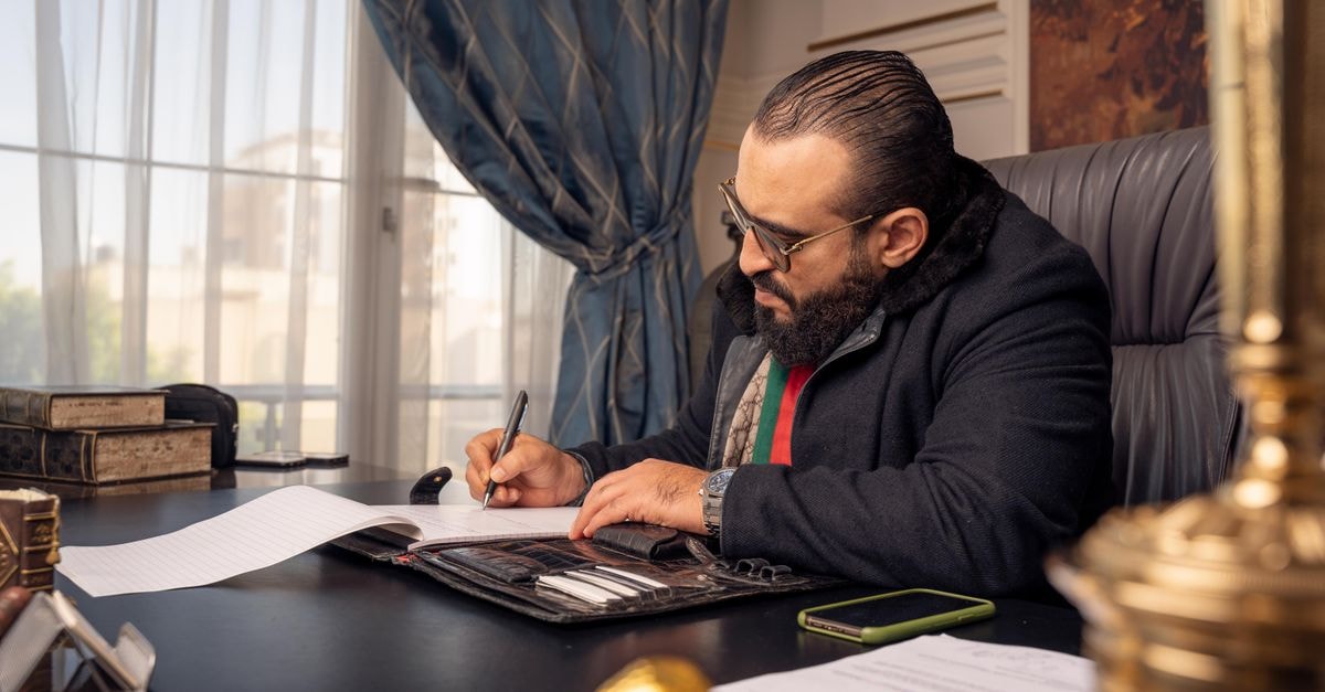 Masters of the Universe Gets October 4K Blu-ray Release After Prime Video Revival Professional man writing at a desk in an elegant office setting, displaying concentration.