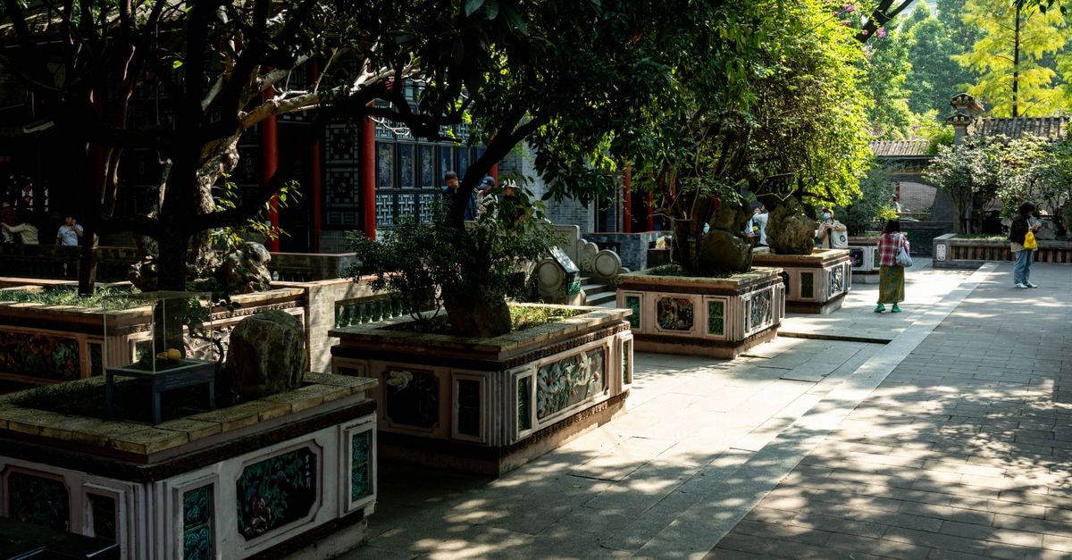 Foshan Travel Guide: Lingnan Roots and Pottery Soul Beautiful temple garden in 佛山市, Guangdong Province, China. Sunlit path surrounded by traditional architecture and lush greenery.