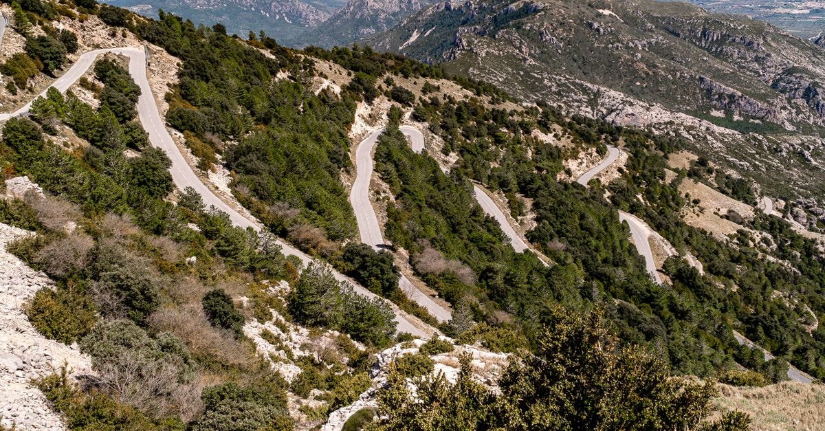 Quneitra Travel Guide: A High-Valley Visit, Carefully Planned A breathtaking view of a zigzag mountain road winding through lush greenery.