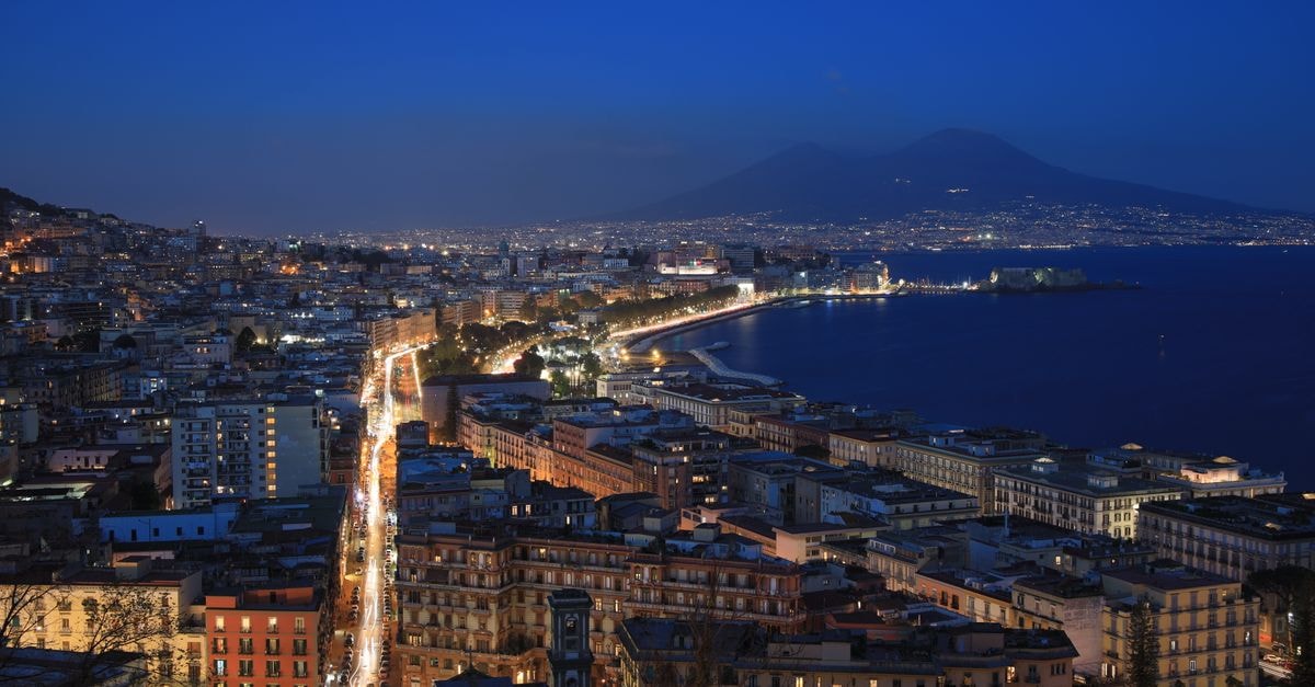 MH Design Hotel Naples: Quiet Via Chiaia Stay Near Piazza del Plebiscito A breathtaking aerial view of Naples cityscape and Mount Vesuvius under evening lights.