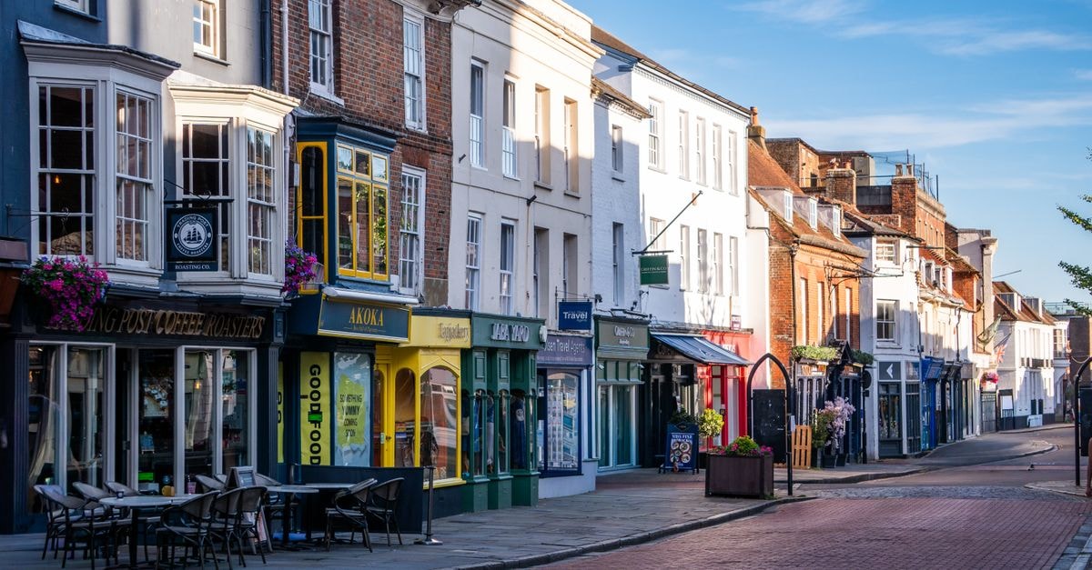 St Albans Travel Guide: Planning Tips, Costs and Things to Do A picturesque English street lined with colorful shops and outdoor seating, bathed in daylight.