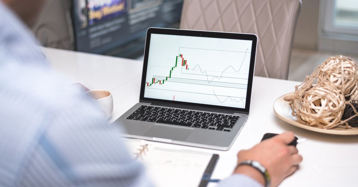 Caterpillar Shares Slide 2.1% as Trading Volume Drops Man reviewing financial analysis on laptop in a modern office setting with focus on trading charts and data.
