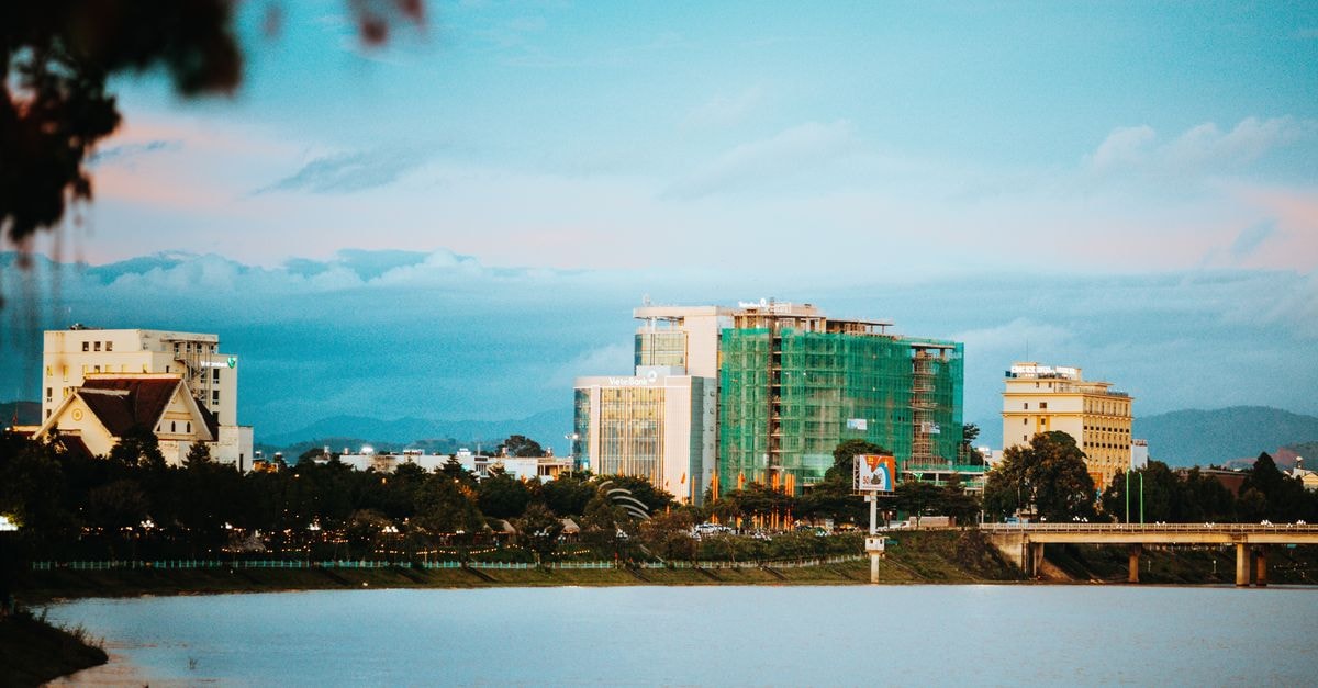 Meliá Vinpearl Hue in Huế: A Riverside Landmark Overlooking the Huong River Peaceful view of Kon Tum's skyline reflecting over water at dusk with clouds visible.