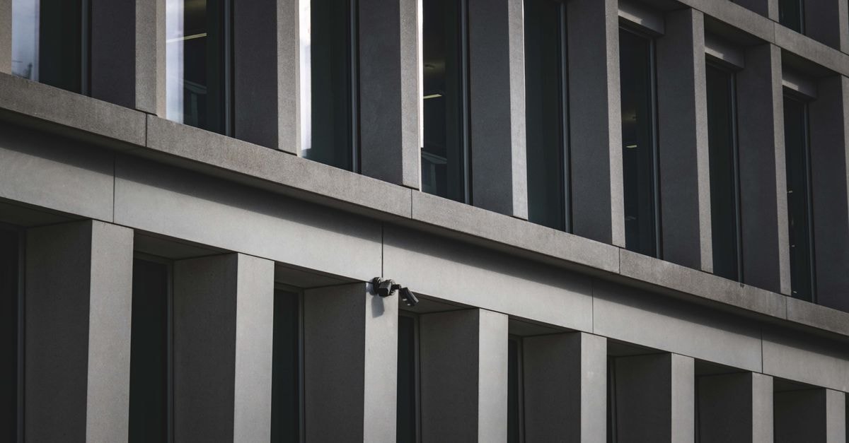 Contemporary office building exterior featuring multiple windows and security cameras.