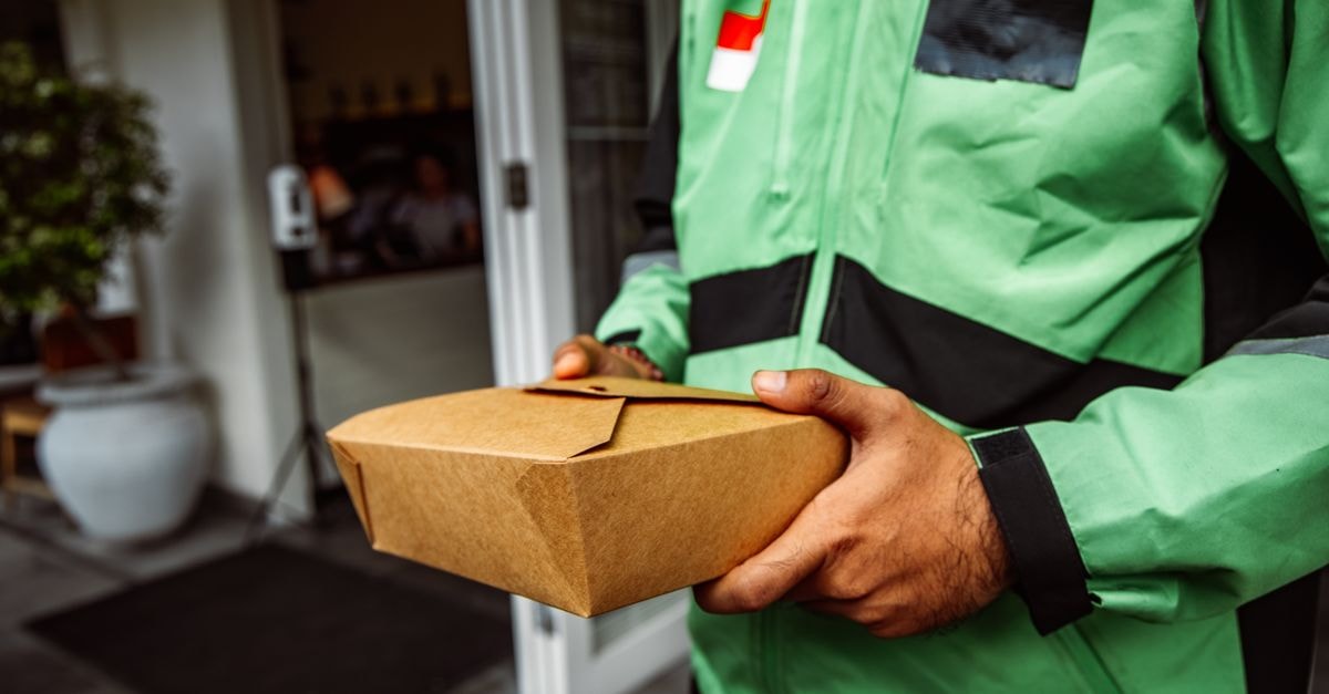 Flowers Foods: Cash Generation Holding Up While the Market Tests the Long-Term Story A deliveryman in a green jacket holding an eco-friendly food package outside a restaurant.
