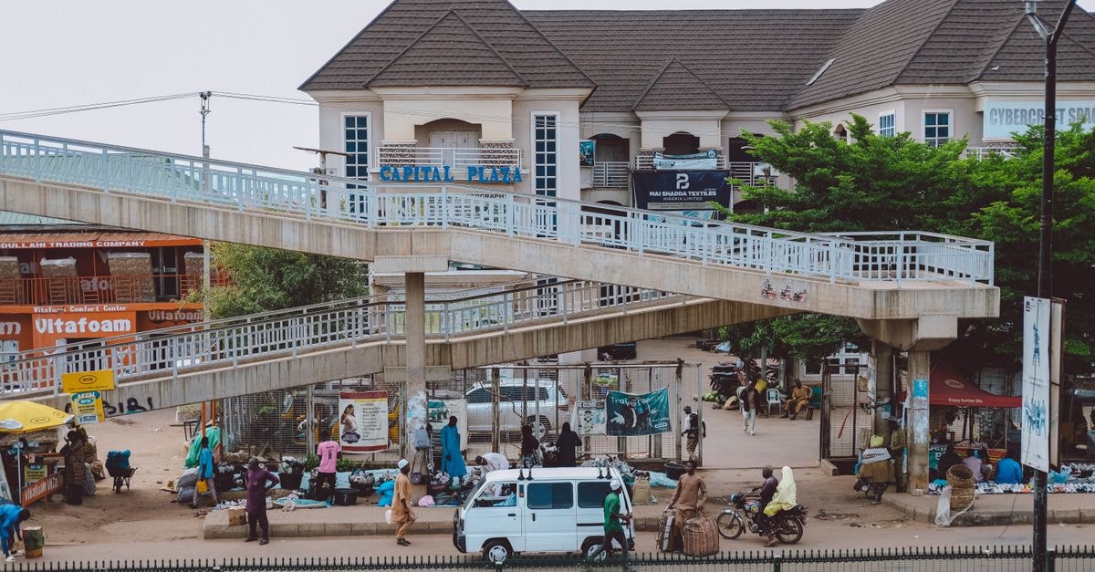 Warri Travel Guide: Planning Tips, Costs and Things to Do Vibrant city life near Capital Plaza with pedestrians, vehicles, and an overpass.