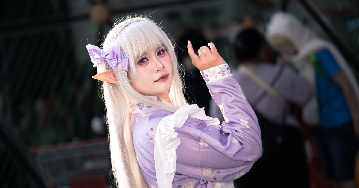 Colorful cosplay of a fantasy elf character with long white hair and purple attire.