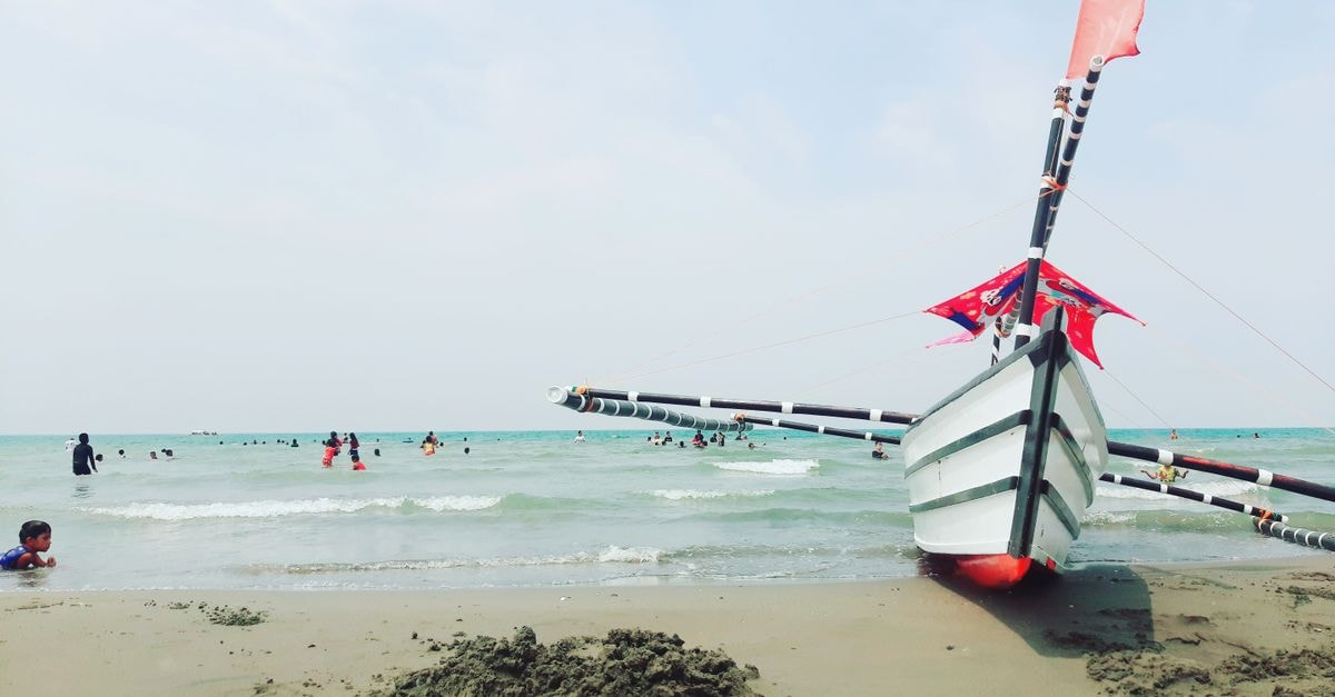 A traditional bangka boat on the sandy shores of San Fabian, Philippines, vibrant summer vibes.