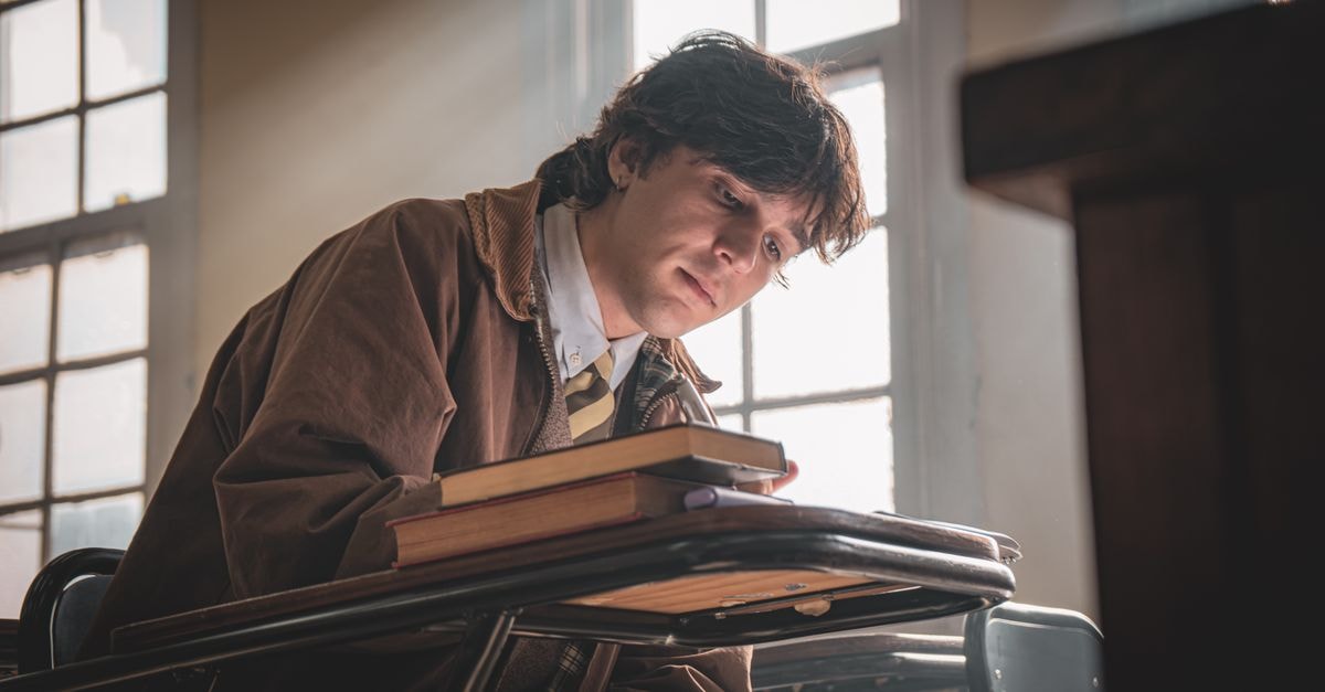 A student deep in thought at a classroom desk, sunlight streaming through the window.