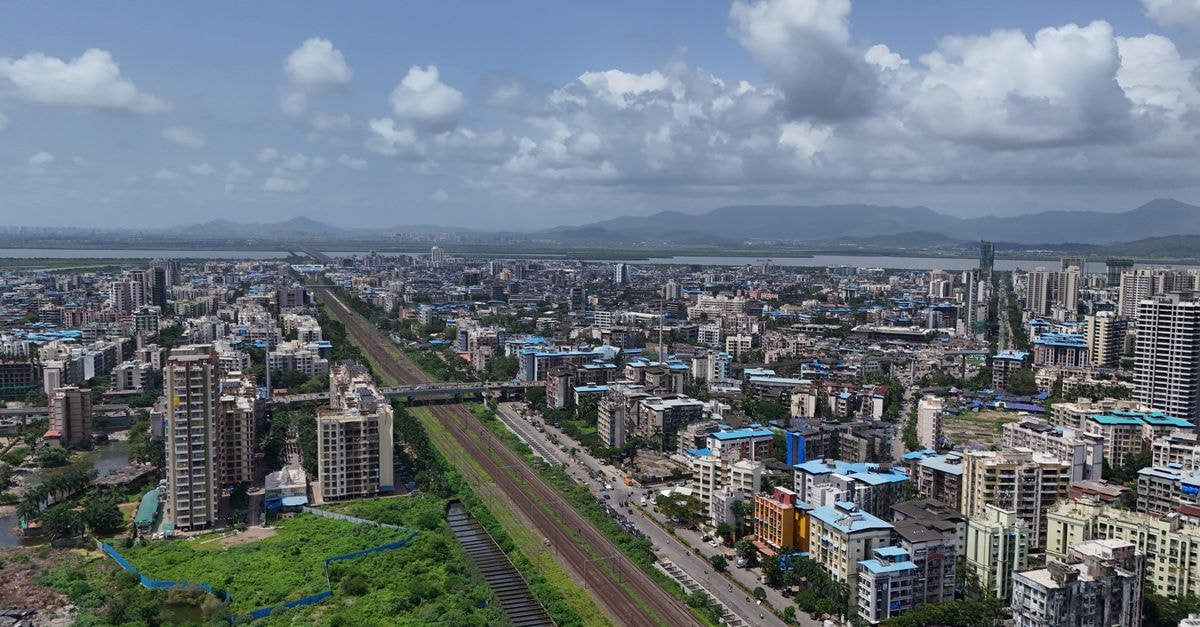 Hotel Manas in Ichalkaranji: A Station Road Stay Near Café Green Aerial shot of Mumbai skyline showcasing tall buildings and green landscapes under a vibrant sky.