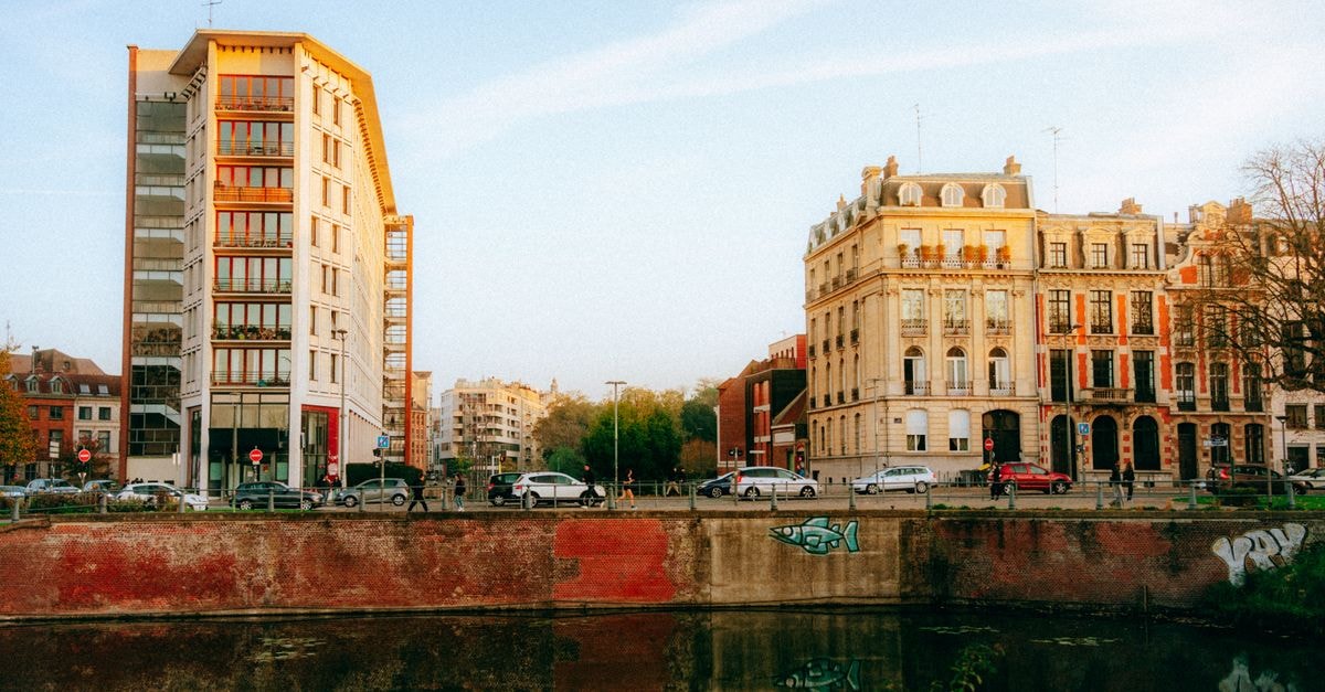 Aparthotel Adagio Lille Centre Grand Place in Lille: Apartment-Style Stay Near Vieux Lille Elegant European architecture along a riverside at sunset, reflecting urban charm.