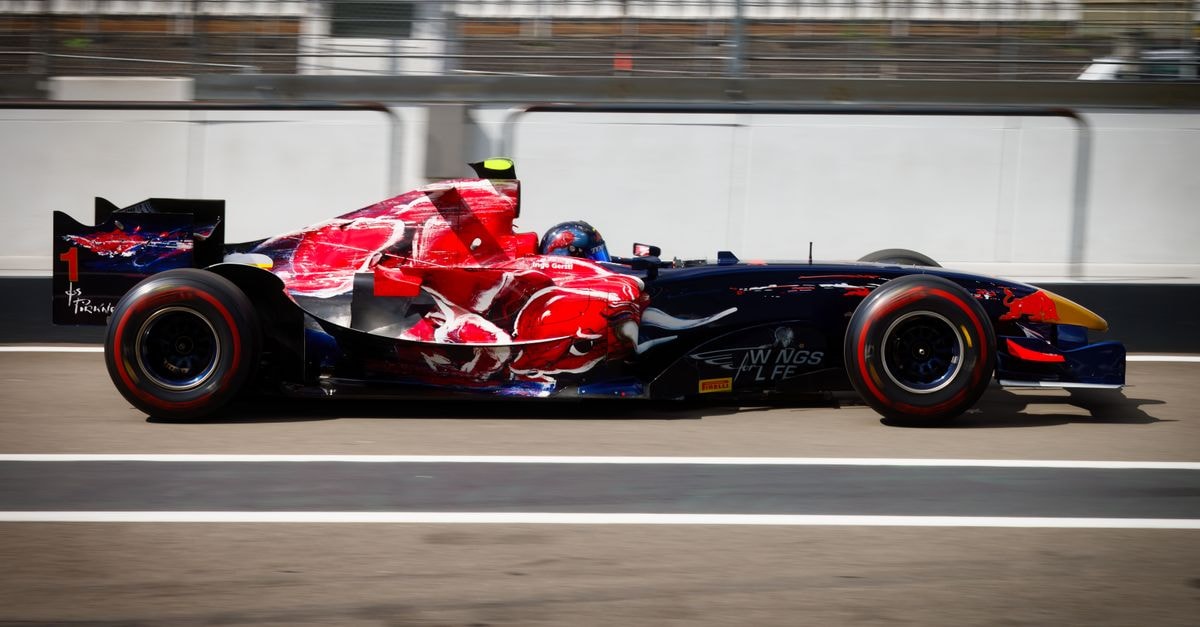 A dynamic shot of a colorful Formula racing car speeding on the track, showcasing motion and speed.