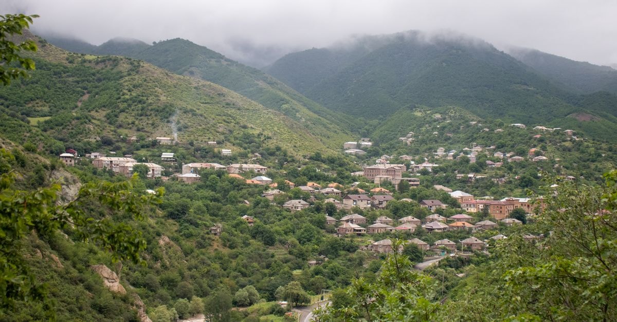 Charming hillside village surrounded by lush green forests and misty mountains.