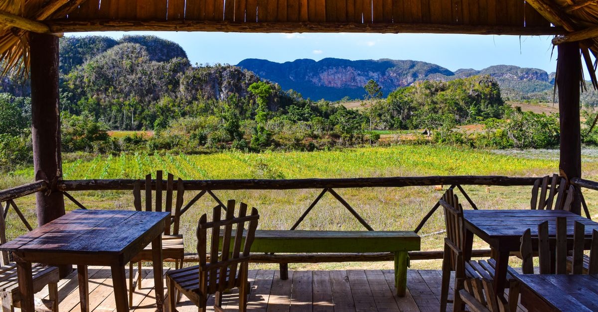Enjoy the stunning view of Vinales Valley, Cuba from a rustic wooden terrace.