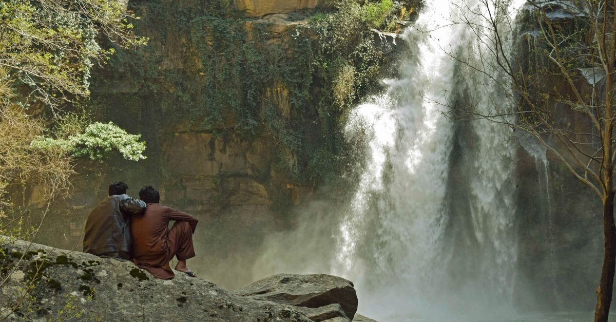 Mingora Travel Guide: A Slow Look at Swat's Largest City Two individuals enjoy the serene view of Shingro Waterfall in Swat Valley, Pakistan.