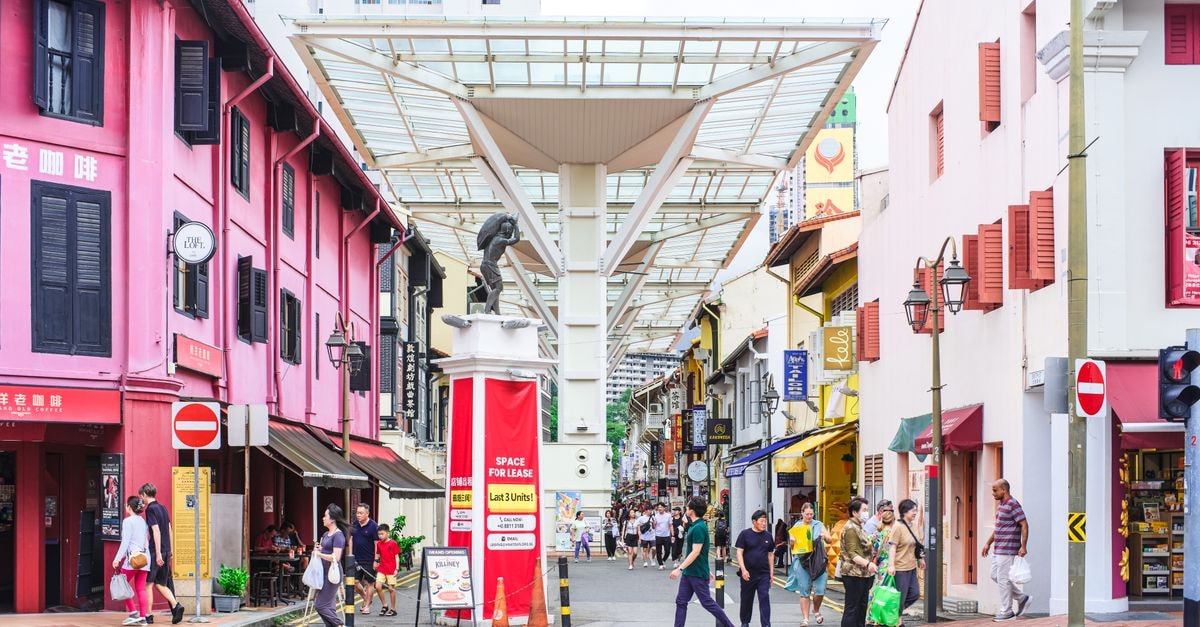 Bustling street scene in Chinatown, Singapore with colorful buildings and people.