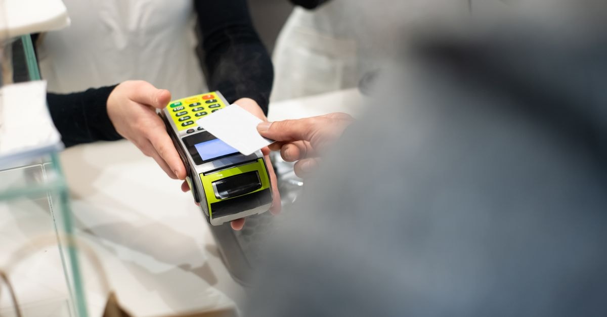 Paysign: Vertical Payment Processor With Improving Unit Economics But Concentrated Customer Risk A customer pays with a card at a payment terminal in a modern retail store.