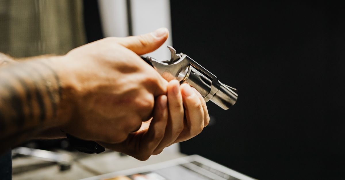 Revolver in Darjeeling: A Beatles-Inspired Cosy Hill Stay A detailed close-up of a person holding a revolver in an indoor setting. Strong focus on hands and firearm.