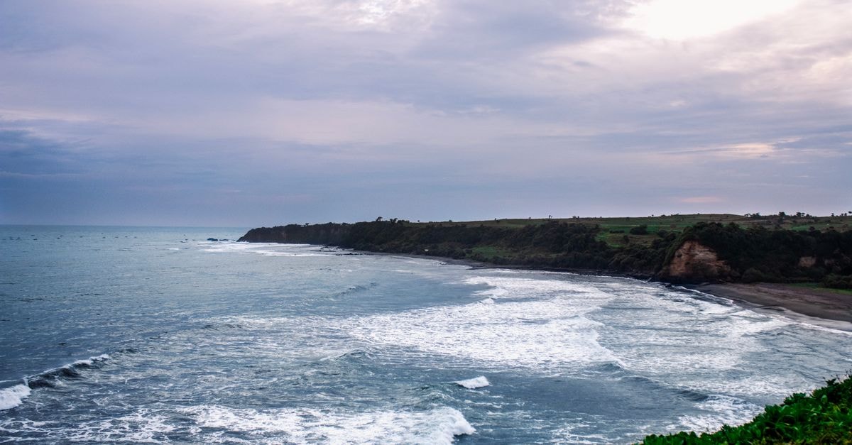 Cilacap travel guide: coastal character beyond Java's main tourist trail Explore the stunning coastline of Puncak Guha, Java with its dramatic waves and expansive ocean views under a cloudy sky.