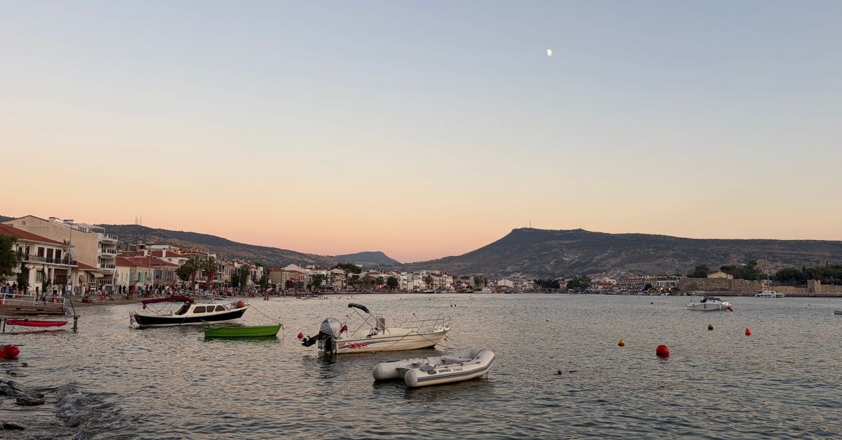 The 1930s, Mytilene — A Neoclassical Stay in the Heart of Lesbos Tranquil sunset over Mytilene harbor, featuring boats and a distant town view under a pastel sky.