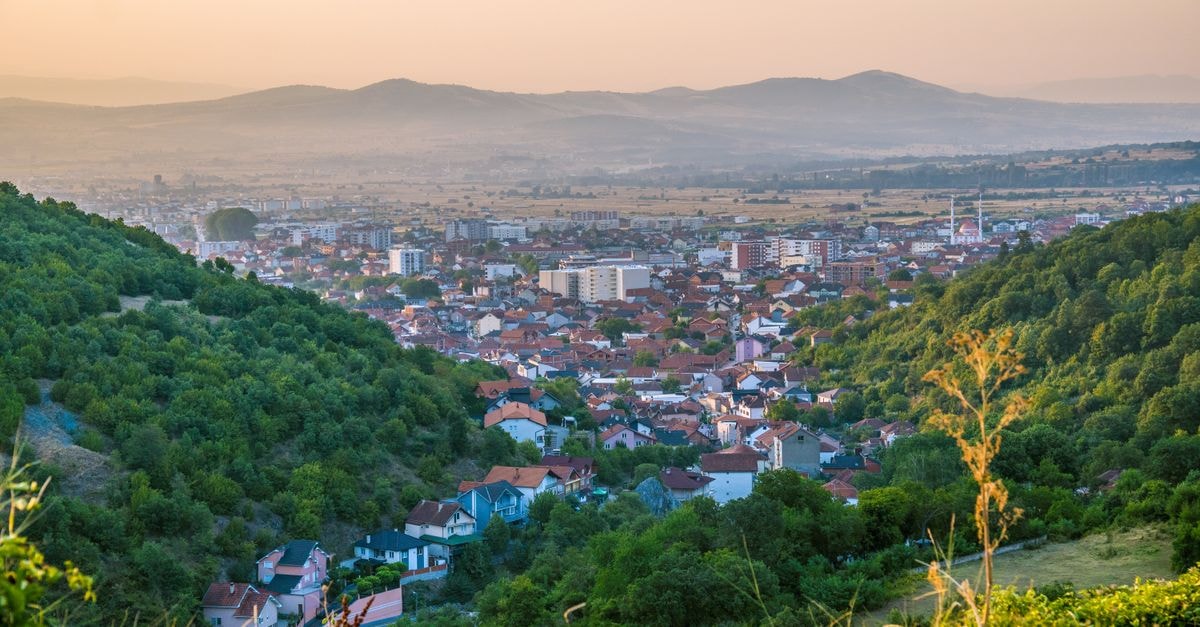 Scenic view of the town of Preševo surrounded by lush hills in Serbia at sunset.