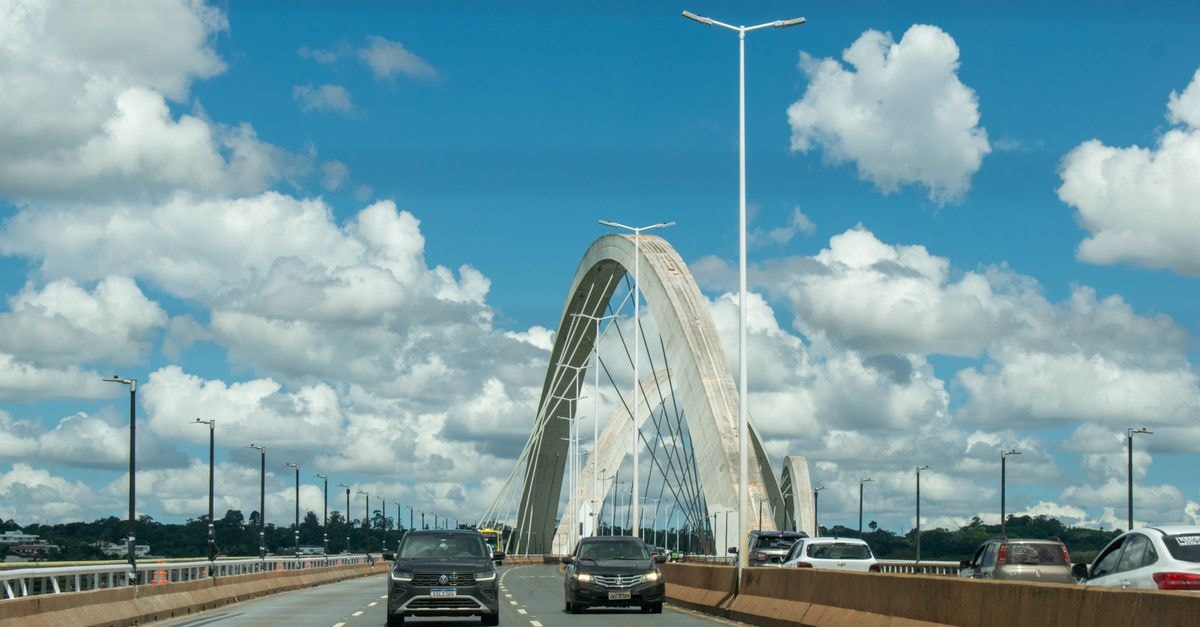 Itabuna Travel Guide: Weather, Transport and Brazilian Flavors Cars driving on the iconic Juscelino Kubitschek Bridge in Brasília, Brazil against a background of fluffy clouds and blue sky.