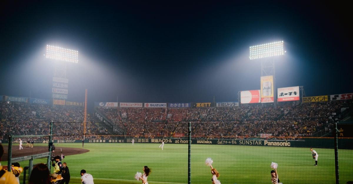 Family sues Franklin Sports after six-year-old girl dies when badminton racket shaft pierces her skull in Maine Thrilling night baseball game at Hanshin Koshien Stadium in Japan with vibrant crowd.