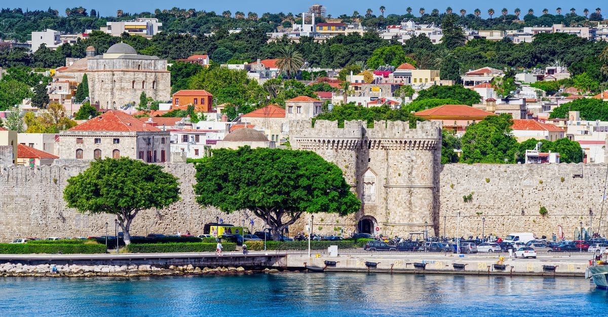 Hotel Ellique in Rhodes: A 14th-Century Old Town Hideaway Beautiful view of the historic fortress in Rhodes, Greece, with vibrant cityscape and waterfront.