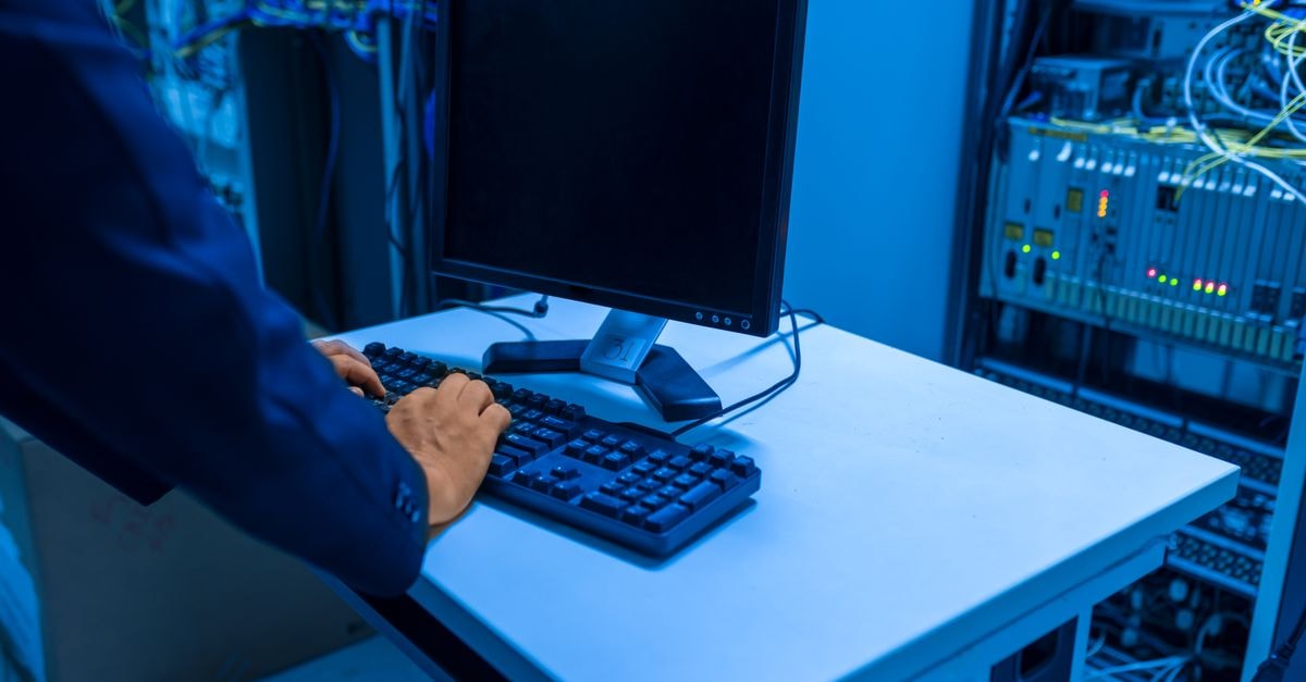 Palo Alto Networks and NTT Data expand AI security alliance, targeting $1 billion in joint revenue by 2029 An IT professional operates a computer in a server room, managing network systems and connected devices.