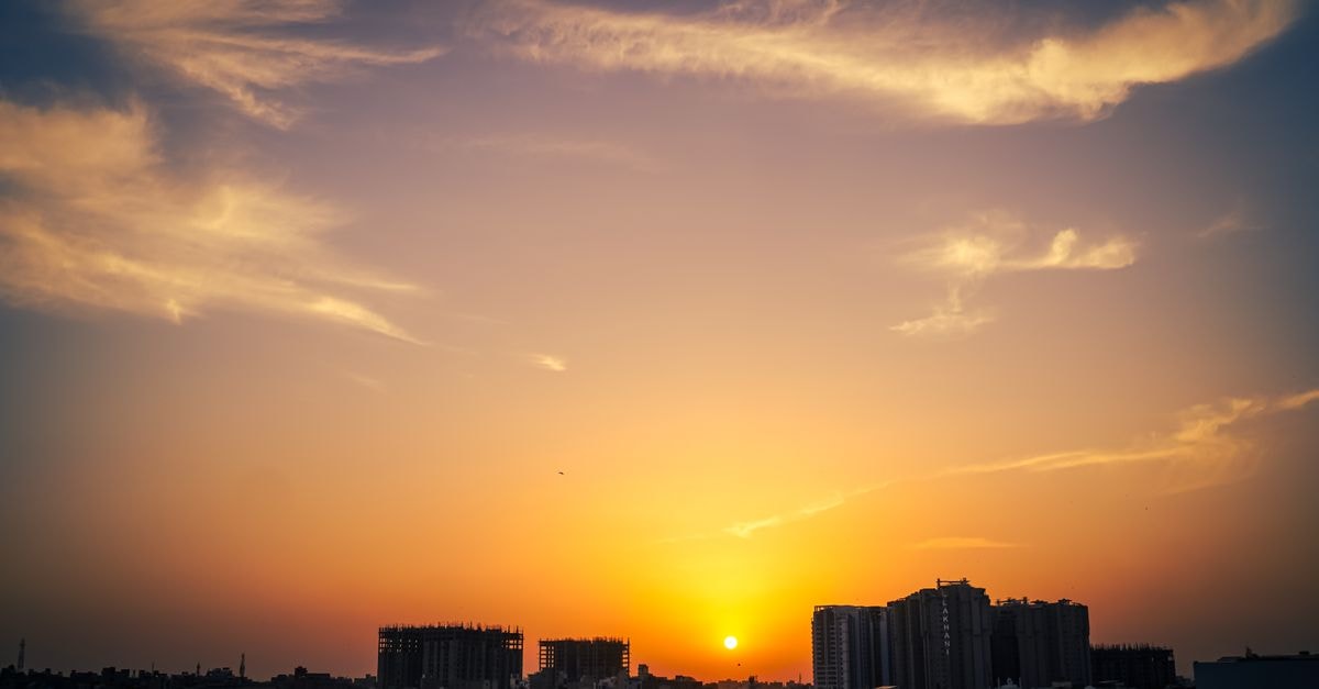 Karwan Hotel, Karachi: A Pocket-Sized Address on Gharib Abad Street Beautiful sunset with dramatic clouds over Karachi's skyline, blending urban architecture with nature.