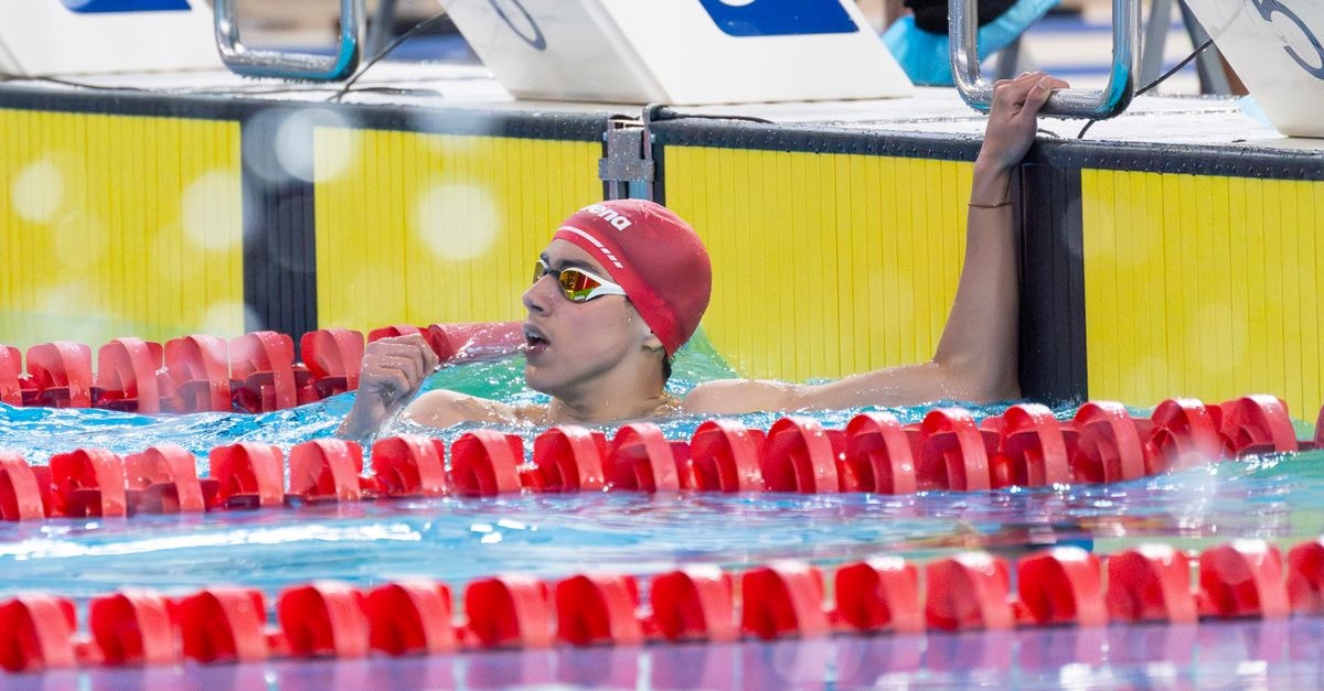 Walsh Closes U.S. Nationals 50m Free Five-Hundredths Off Own World Record, Dressel Posts Fastest Sprint in Four Years Swimmer in red cap and goggles finishes a race, holding lane divider. Celebrating victory.