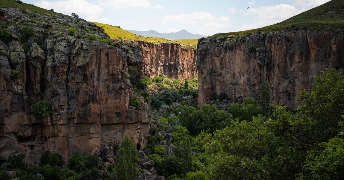 Explore the stunning Ihlara Valley with vibrant green foliage and majestic canyon walls in Aksaray, Türkiye.