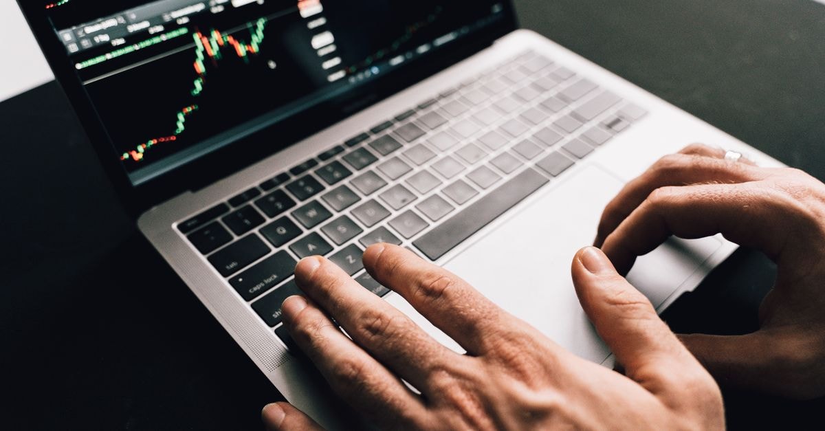 Tesla sets September 3 Cybercab launch event in Austin Close-up of hands typing on a laptop with stock market graphs, ideal for finance or business themes.