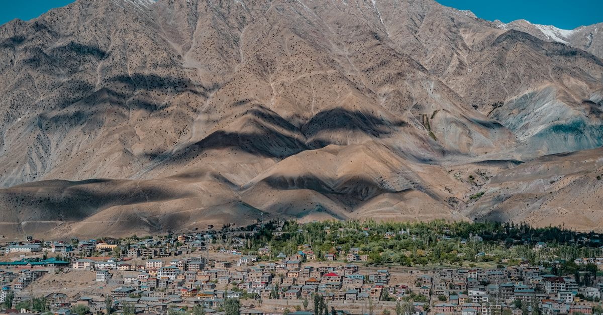 PTDC Motel Skardu in Skardu: Riverside Stays Below the Karakoram Stunning aerial view of Leh town nestled against rugged mountain backdrop in clear blue skies.