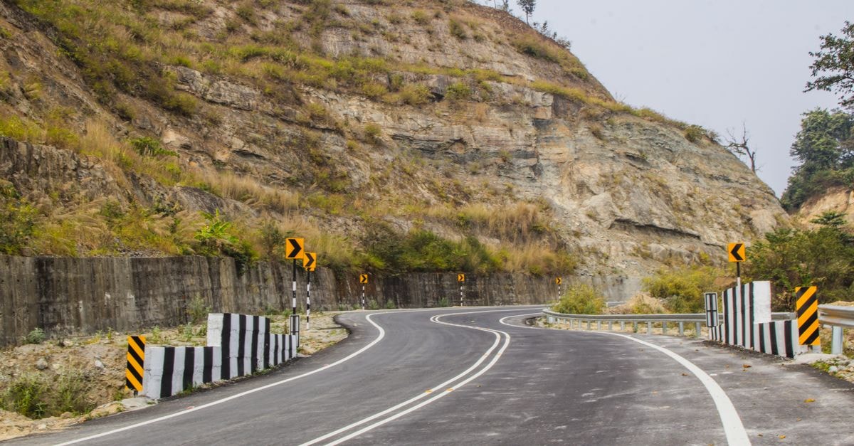 A scenic curved road through mountainous terrain under a clear sky, ideal for adventure travel.