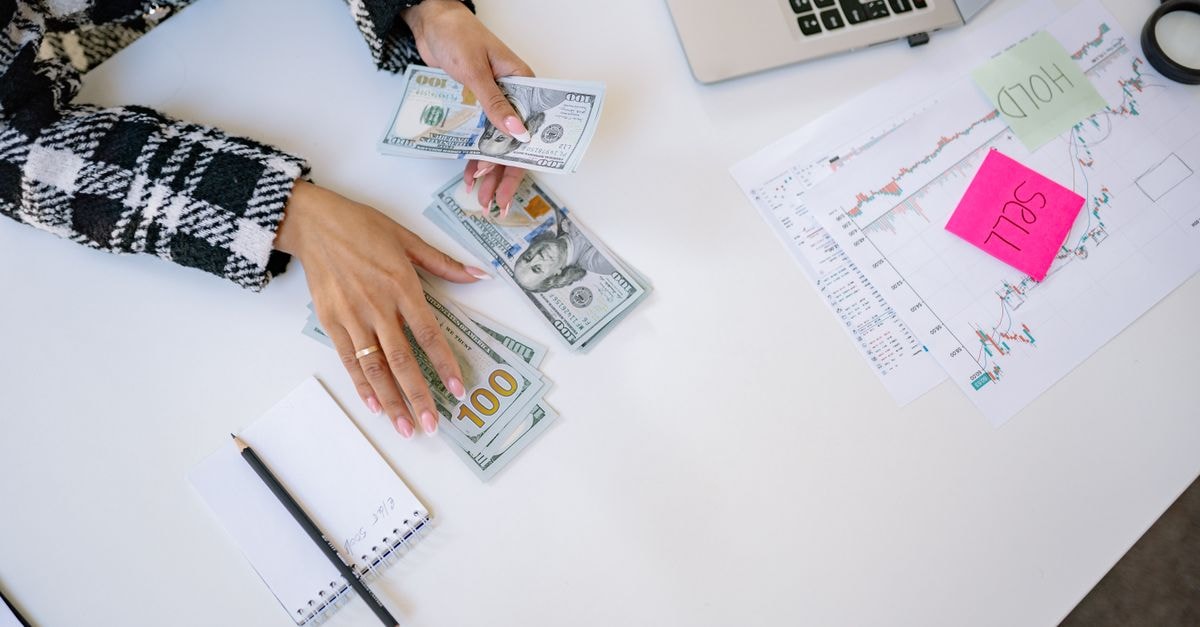 ICICI Bank Prices USD 500 Million Senior Notes Under GMTN Programme Businesswoman counting dollar bills with financial charts and laptop on table. Investment and finance concept.